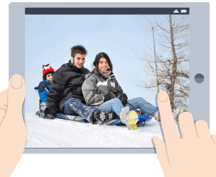 A tablet device showing 3 young people tobogganing in the snow.